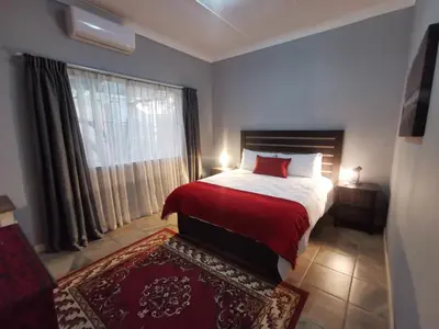 a bedroom with a bed with a red blanket and a window at 34th on Pierneef in Pretoria