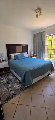 a bedroom with a large bed with a blue comforter at Mooikloof Ridge Hide Out in Pretoria