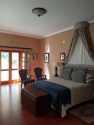 a bedroom with a bed and two chairs and a window at Old Mine Guesthouse in Musina