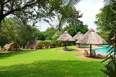 a resort with a pool and some grass and umbrellas at Pestana Kruger Lodge in Malelane