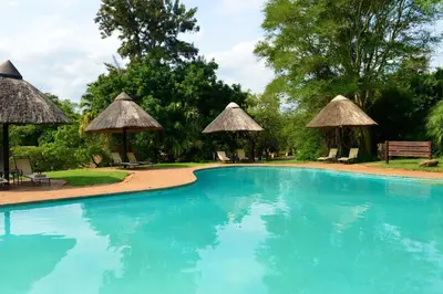 a large swimming pool with umbrellas and chairs at Pestana Kruger Lodge in Malelane
