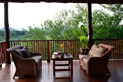 a porch with two chairs and a couch and a table at Pestana Kruger Lodge in Malelane