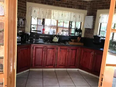 a kitchen with red wooden cabinets and windows at Big Tuskers Bush Camp in Marloth Park
