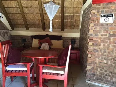a table and chairs in a room with a brick wall at Big Tuskers Bush Camp in Marloth Park