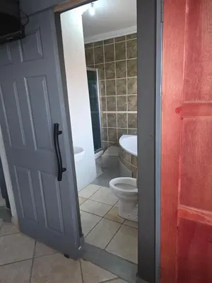 a bathroom with a toilet and a door open at The Good Samaritan 2 in Witbank