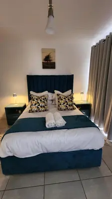 a bedroom with a large blue bed with pillows at White House At The Blyde Crystal Lagoon in Pretoria