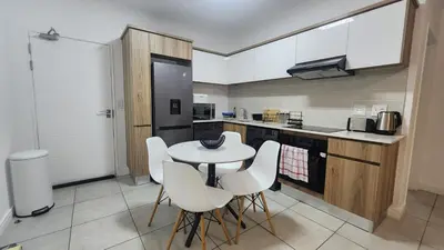 a kitchen with a white table and white chairs at White House At The Blyde Crystal Lagoon in Pretoria