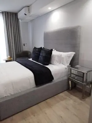 a bedroom with a large bed and a side table at Ellipse Lux Hotel - Apartment in Midrand