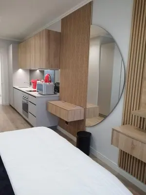 a room with a bed and a mirror and a kitchen at Ellipse Lux Hotel - Apartment in Midrand