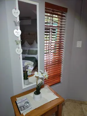a room with a mirror and a table with flowers at Lily's Inn in Centurion