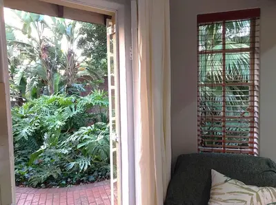 an open door to a patio with a couch and plants at Lily's Inn in Centurion