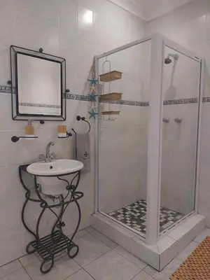 a bathroom with a shower and a sink and a mirror at Lily's Inn in Centurion