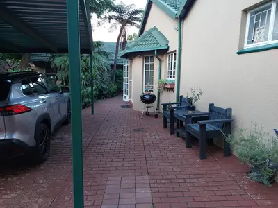 a patio with benches and a car parked next to a house at Lily's Inn in Centurion