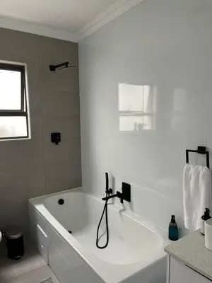 a white bath tub in a bathroom with a window at Condo in Sunninghill, Sandton in Sandton