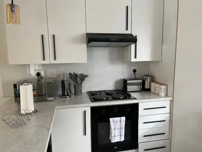 a kitchen with white cabinets and a stove top oven at Condo in Sunninghill, Sandton in Sandton