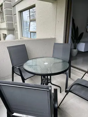 a glass table and chairs on a patio at Condo in Sunninghill, Sandton in Sandton