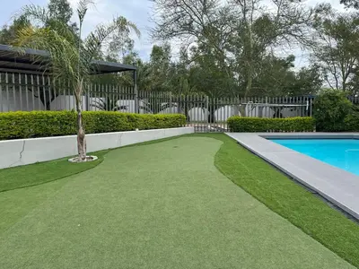 a yard with a swimming pool and a palm tree at Condo in Sunninghill, Sandton in Sandton