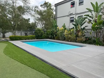 a swimming pool in a yard next to a house at Condo in Sunninghill, Sandton in Sandton