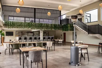 a restaurant with tables and chairs and a staircase at The Legacy Hotel and Spa in Tzaneen