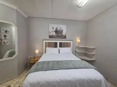 a bedroom with a large white bed and a mirror at 153 A Marshall in Polokwane