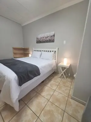 a bedroom with a large white bed and a table at 153 A Marshall in Polokwane