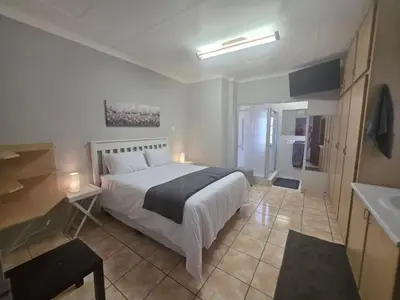 a bedroom with a large bed and a bathroom at 153 A Marshall in Polokwane