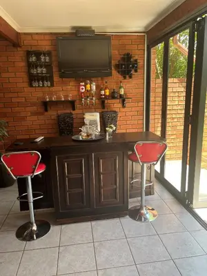 a bar with two chairs and a television on a brick wall at Garys Place -Work-ready, family-friendly, and braai-happy in Centurion