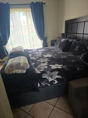 a bedroom with a bed with a black comforter at Garys Place -Work-ready, family-friendly, and braai-happy in Centurion