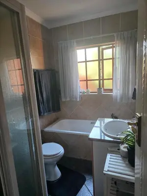 a bathroom with a tub and a toilet and a sink at Garys Place -Work-ready, family-friendly, and braai-happy in Centurion