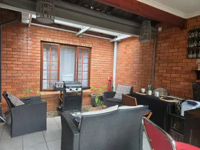 a patio with tables and chairs and a brick wall at Garys Place -Work-ready, family-friendly, and braai-happy in Centurion