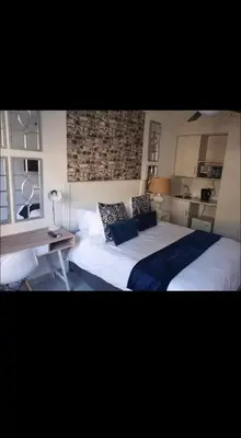 a bedroom with a large bed and a desk and windows at Soteria House in Kempton Park