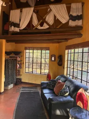 a living room with a leather couch and windows at Reverie Safari Lodge, Marloth Park in Marloth Park