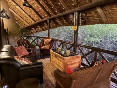 a living room with couches and chairs on a balcony at Reverie Safari Lodge, Marloth Park in Marloth Park