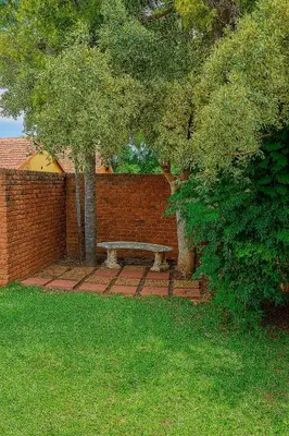 a brick wall with a bench next to a tree at Roots of Grace in Polokwane