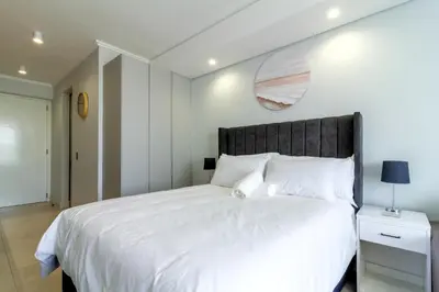 a bedroom with a white bed with a black headboard at Ellipse Waterfall 4212 in Midrand