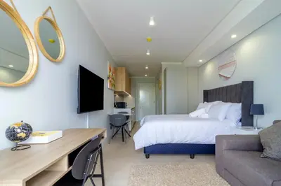a bedroom with a bed and a desk and a couch at Ellipse Waterfall 4212 in Midrand