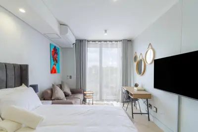 a bedroom with a bed and a couch and a tv at Ellipse Waterfall 4212 in Midrand