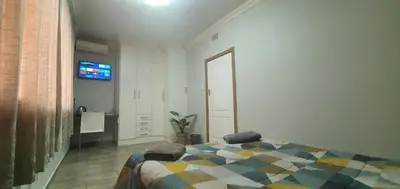 a bedroom with a bed and a tv on the wall at 329 on 30th Avenue Villieria Drian in Pretoria