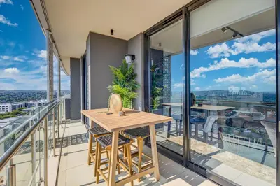 a balcony with a wooden table and chairs on it at 2 Bed 2 Bath Apartment, Ellipse, Waterfall in Midrand