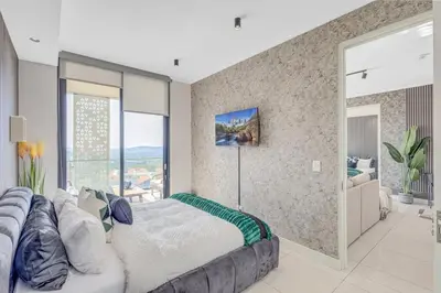a bedroom with a large bed and a couch at 2 Bed 2 Bath Apartment, Ellipse, Waterfall in Midrand