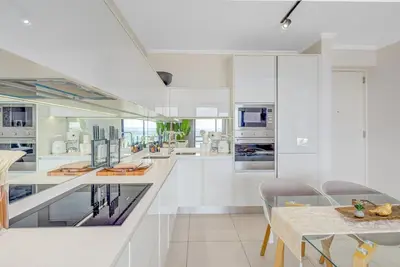a kitchen with white cabinets and a table and chairs at 2 Bed 2 Bath Apartment, Ellipse, Waterfall in Midrand