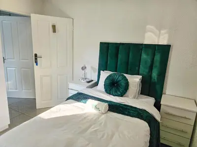 a bedroom with a bed with a green headboard at The M GuestHouse in Kempton Park