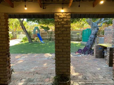an outdoor patio with a brick wall and a playground at Springbok 47 in Polokwane