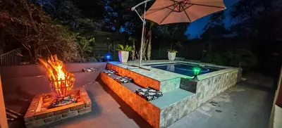 a swimming pool with a fire pit and an umbrella at Marloth Birdhaven in Marloth Park