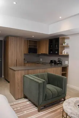 a living room with a green couch and a kitchen at The Hideaway at Menlyn Maine Trilogy in Pretoria