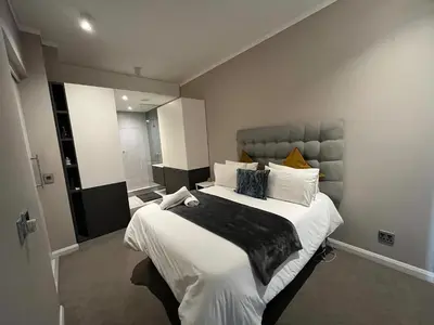 a bedroom with a large bed with white sheets and pillows at The Hideaway at Menlyn Maine Trilogy in Pretoria