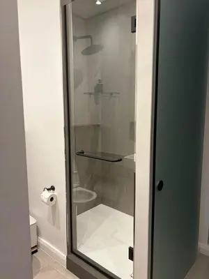 a glass shower in a bathroom with a roll of toilet paper at The Hideaway at Menlyn Maine Trilogy in Pretoria