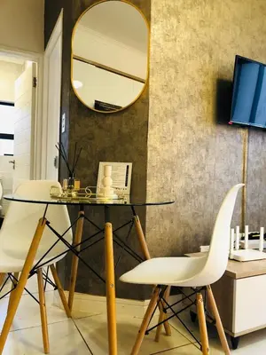 a glass table with two white chairs and a mirror at Apartment at the Blyde in Pretoria