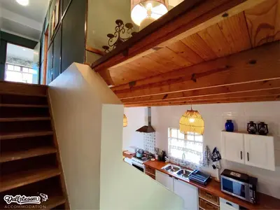 a kitchen with wooden ceilings and a staircase in a house at Amber & Birch in Dullstroom
