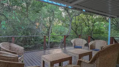 a deck with wicker chairs and tables and trees at 2219 Kruger Wild in Marloth Park
